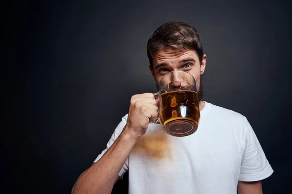 Homme avec une tasse de bière dans un t-shirt blanc émotions style de vie ivre sur un fond sombre isolé — Photo