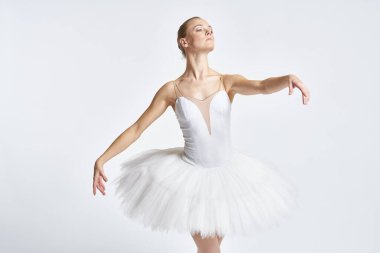 Beyaz etekli balerin dans egzersizi yapıyor. Esnek arka plan.