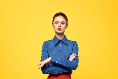 Mavi gömlekli çekici bir kadın, elleri ve kırmızı eteği ile işaret ediyor sarı arka plan portresi kesilmiş.