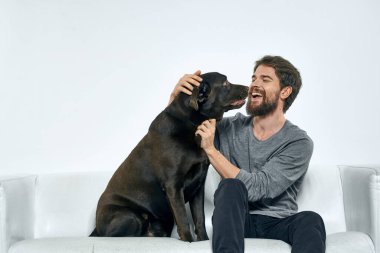Kanepede evcil köpeği olan bir adam. Arkadaşlarıyla eğleniyor.
