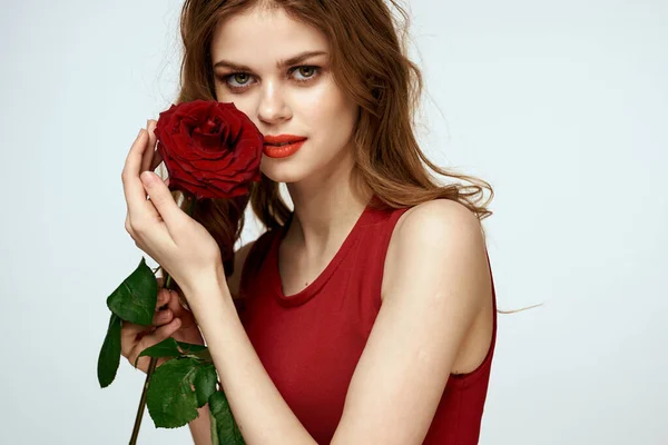 Piękna kobieta w czerwonej sukience posiada różę w dłoni prezent kwiaty dekoracji atrakcyjny wygląd — Zdjęcie stockowe