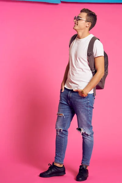 Портрет чоловіка в білій футболці і з рюкзаком на спині сонцезахисні окуляри рожевий фон моделі — стокове фото