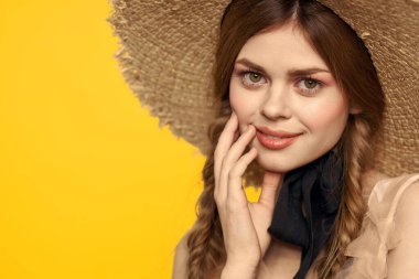 Şapkalı romantik bir kadın sarı arka planda eğleniyor ve güneş gözlüğü siyah kurdele modeli portresi takıyor.