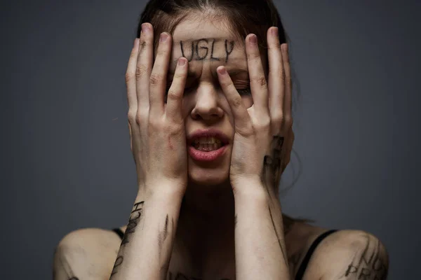 Mujer con inscripciones ofensivas en su cuerpo tocándose con las manos estrés frustración odio — Foto de Stock