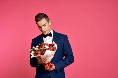 Çiçek buketi ve pembe arka planda papyonlu romantik bir adam.