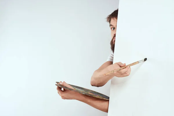 Male artist hiding behind an easel palette drawing art — Stock Photo, Image