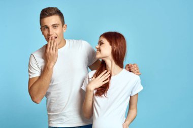 Beyaz tişörtlü hamile bir kadın ve evli bir çift, bebek mavisi bir arka plan bekliyor. Duyguların görüntüsü değişmiş.