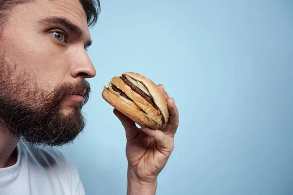 Emotionele man hamburger fast food dieet voedsel close-up blauwe achtergrond — Stockfoto