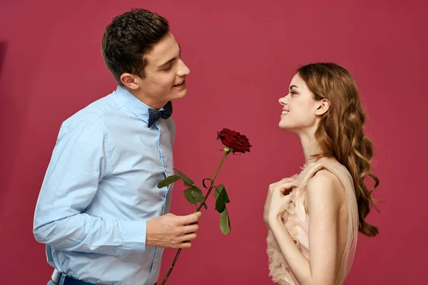Hombre y mujer enamorados con una flor roja sobre un fondo rosa abrazarse Copiar espacio — Foto de Stock
