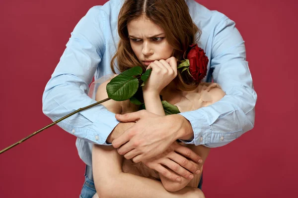Hombre y mujer enamorados con una flor roja sobre un fondo rosa abrazarse Copiar espacio — Foto de Stock