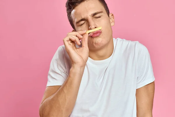 Lindo hombre con papas fritas en las manos emociones modelo de comida rápida rosa fondo recortado ver de cerca — Foto de Stock