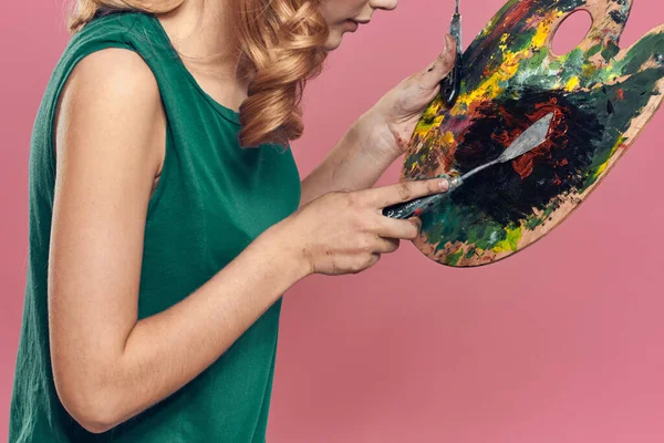 Woman artist green dress easel eat drawing art pink background