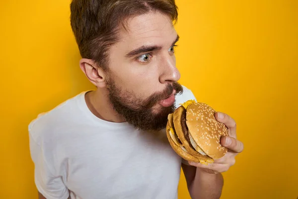 Mann mit Hamburger in den Händen von Fast-Food-Diät weißes T-Shirt Nahaufnahme gelber Hintergrund — Stockfoto