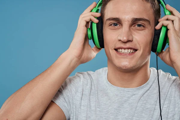 戴绿色耳机的男人听音乐娱乐生活方式白色T恤蓝色背景 — 图库照片