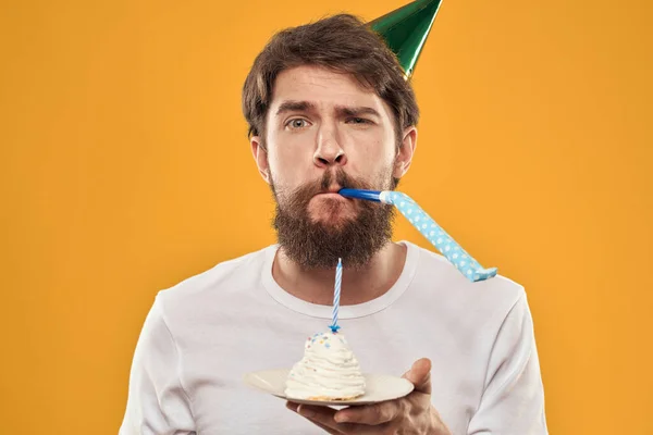 Beau homme avec une barbe et dans une casquette célébrant une fête d'anniversaire fond jaune — Photo
