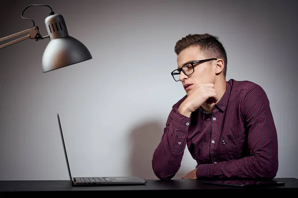 Gözlüklü ve gömlekli bir işadamı açık dizüstü bilgisayarlı bir masada oturuyor. — Stok fotoğraf