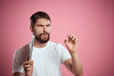 Pembe arka planda dizüstü bilgisayarı olan duygusal adam kırpılmış görünüm kopyalama alanı