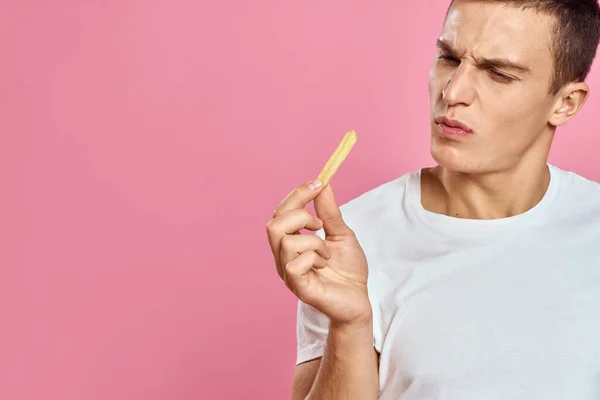Lindo hombre con papas fritas en las manos emociones modelo de comida rápida rosa fondo recortado ver de cerca — Foto de Stock