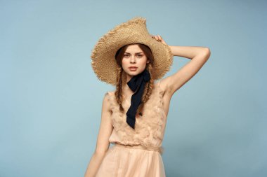 Mavi arka planda pembe elbiseli bir kız elleriyle romantik modeller yapıyor.
