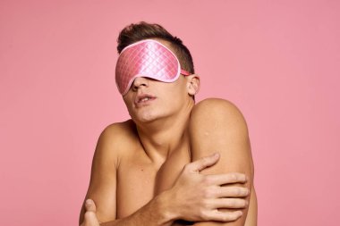 Yüzünde uyku maskesi olan çıplak bir adam pembe arka planda fotokopi çekiyordu.