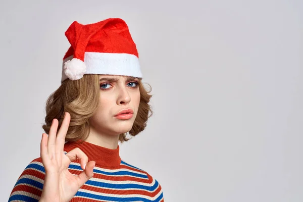 Mulher feliz em um boné de Natal e um suéter listrado gestos com as mãos para os feriados de Ano Novo — Fotografia de Stock