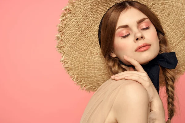 Porträtt av en flicka i en halmhatt på en rosa bakgrund känslor närbild vacker ansikte modell flätor — Stockfoto