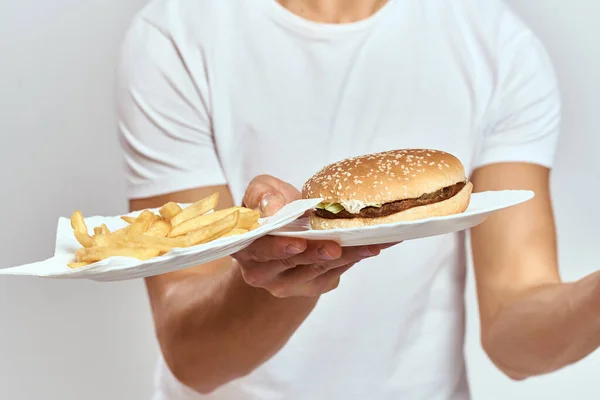 한 남자가 감자튀김과 햄버거를 등에 업고 흰색 티셔츠를 클로즈업 한 사진 복사 우주 모델 — 스톡 사진