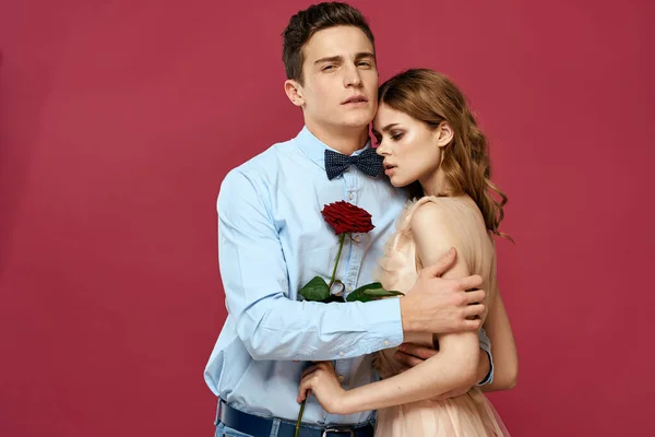 Szerelmes férfi és nő egy piros virág egy rózsaszín háttér ölelés egymást másolás tér — Stock Fotó