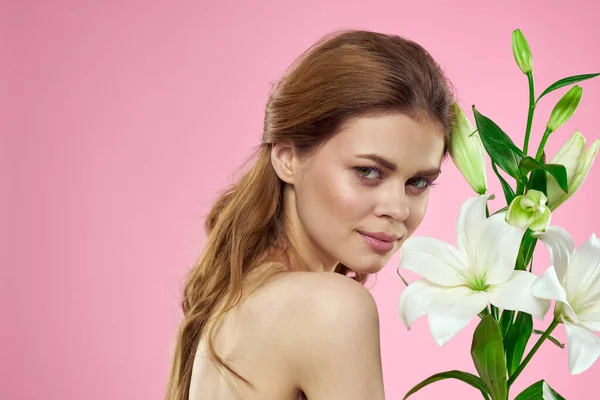 Mujer bonita sosteniendo ramo de flores en los hombros desnudos encanto de fondo rosa — Foto de Stock