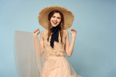 Mavi arka planda pembe elbiseli bir kız elleriyle romantik modeller yapıyor.
