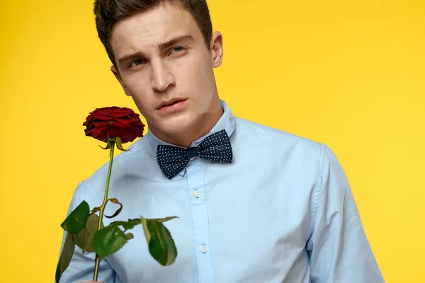 Portrait d'un homme avec une rose rouge sur fond jaune et une chemise légère noeud papillon gentleman — Photo