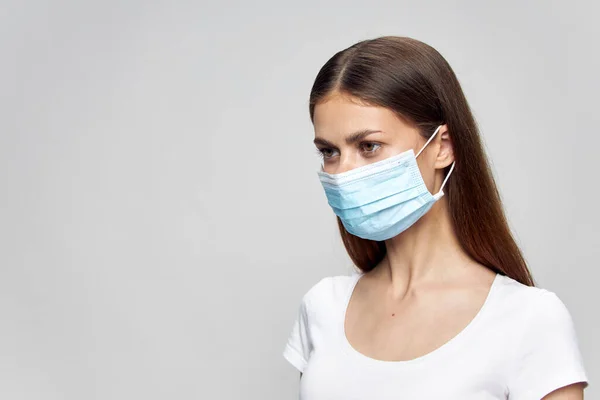 Chica con una máscara médica en su cara mira hacia el espacio de copia — Foto de Stock