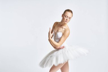 Beyaz etekli balerin dans egzersizi yapıyor. Esnek arka plan.