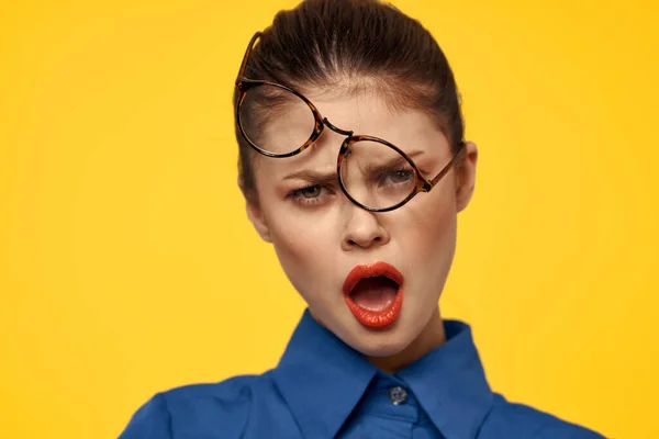 Emotional woman with glasses on her face grimacing on yellow background — Stock Photo, Image