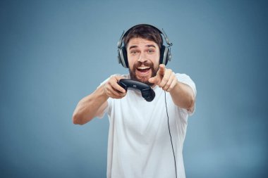 Kulaklıklı bir adam elinde oyun konsolu yaşam tarzı duyguları oynuyor mavi arka plan beyaz tişörtü