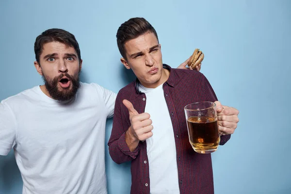 Dwoje wesołych pijanych przyjaciół pijących piwne emocje na niebieskim tle — Zdjęcie stockowe