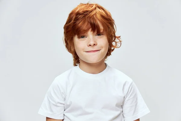 Κόκκινο αγόρι κοιτάζει μπροστά χαμόγελο λευκό t-shirt παιδική ηλικία περικοπή άποψη — Φωτογραφία Αρχείου