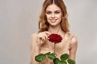 Elinde gül olan kızıl saçlı bir kadın açık arkaplanda duygu modeli portresi.