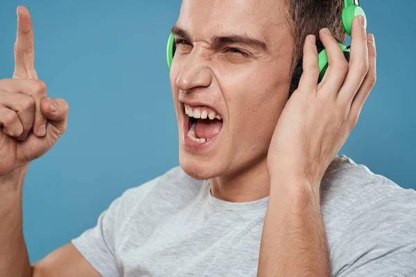 Homem em fones de ouvido verdes escuta música entretenimento estilo de vida branco t-shirt azul fundo — Fotografia de Stock