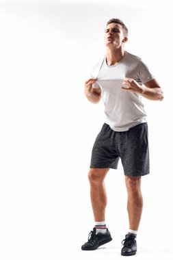 Hafif bir geçmişi olan atletik bir adam tam boy ve koşu şortu spor ayakkabısı tişörtü giyiyor.