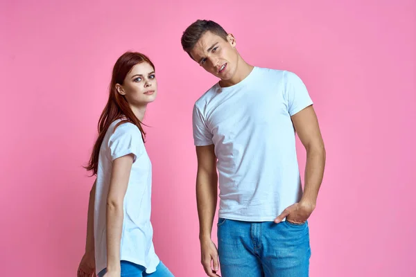 Коханці чоловік і жінка в джинсах і футболці на рожевому тлі обрізаний вид сімейний роман підлітків — стокове фото