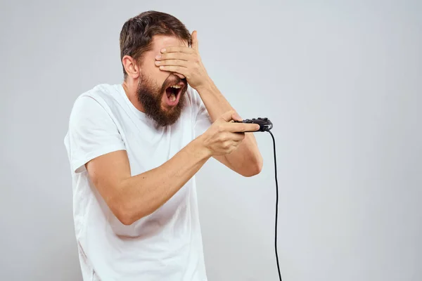 Un hombre con un mando en sus manos jugando juegos ocio estilo de vida tecnología blanco camiseta fondo claro —  Fotos de Stock