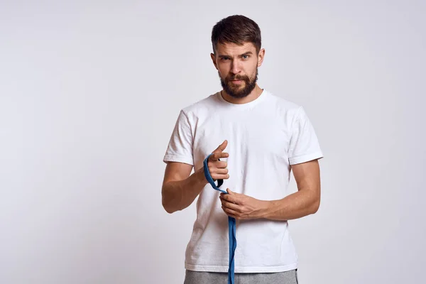 Uomo sportivo in t-shirt bianca blu bendaggi da boxe sulle braccia esercizi di allenamento — Foto Stock