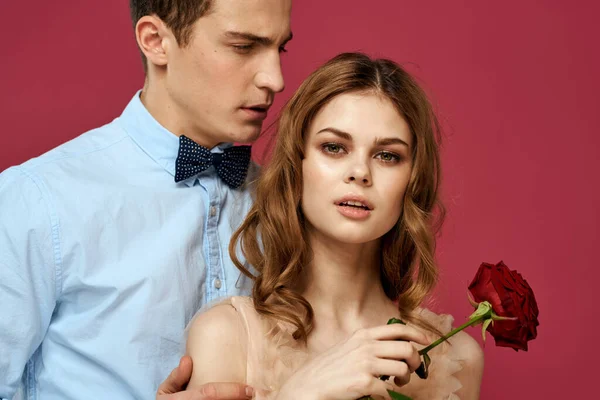 Geliefden mensen met roos in handen op roze geïsoleerde achtergrond knuffel emoties geluk romantiek gevoelens — Stockfoto