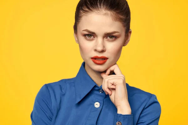 Retrato de una mujer en una camisa azul con brillante maquillaje labios rojos fondo amarillo vista recortada — Foto de Stock