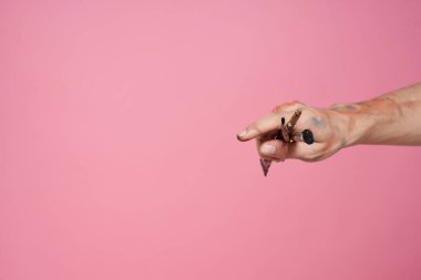 Elleri fırçalı bir adam pembe arka plan hobisi yaratıcı yaklaşımı boyuyor.