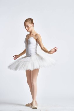Beyaz etekli balerin dans egzersizi yapıyor. Esnek arka plan.