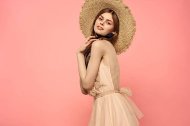 Şapkalı ve siyah kurdeleli güzel bir kadın. Pembe arka plan modeli.