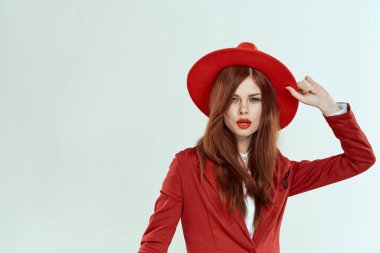 Kırmızı şapkalı güzel bir kadın. Ceket, şık makyaj, hafif arka plan stüdyosu.