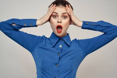 Açık arkaplanda kırmızı dudaklı ve mavi gömlekli güzel bir kadının portresi.